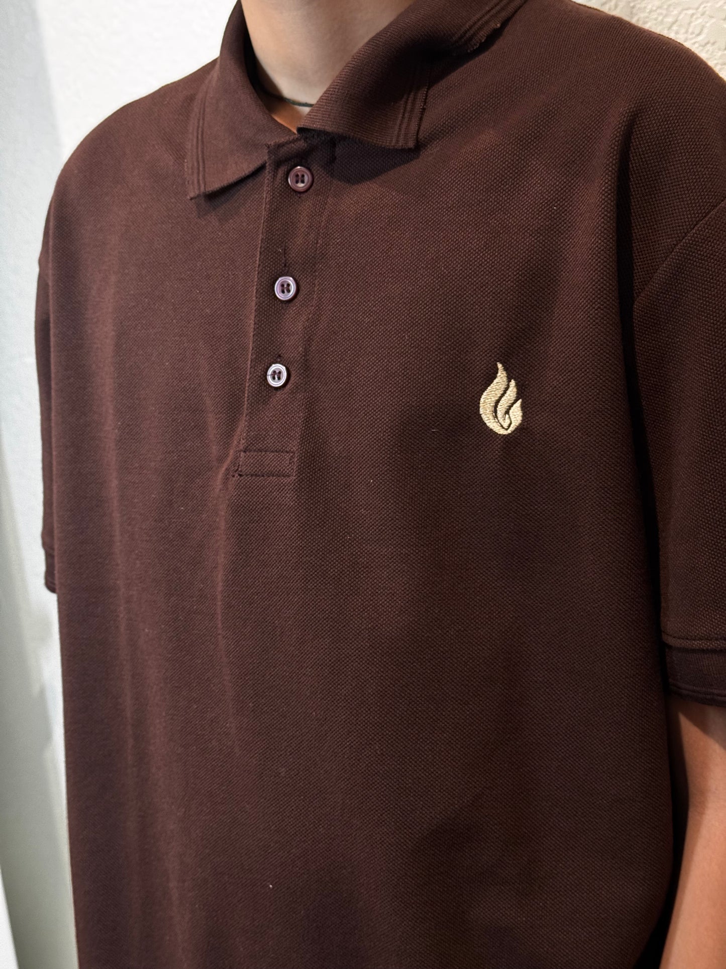 Brown polo shirt with a small kavazs logo on a plain background