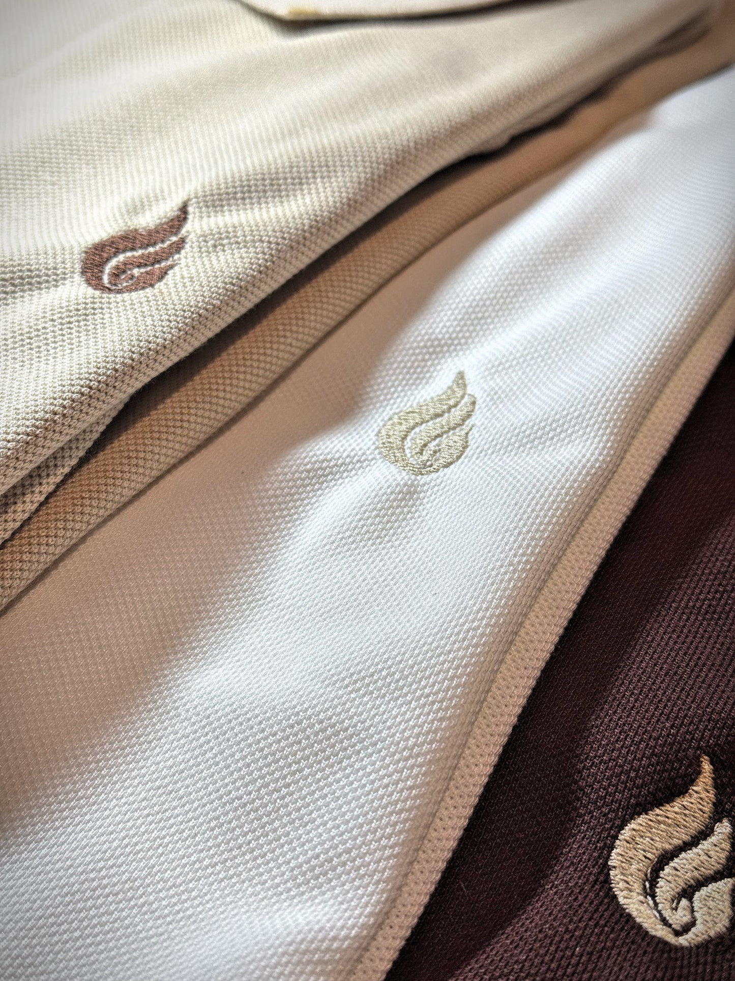 Close-up of a beige fabric with embroidered leaf designs on a brown background