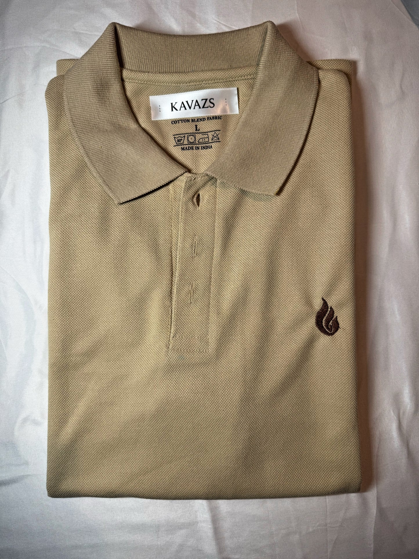 Folded beige polo shirt with a kavazs logo on a light background